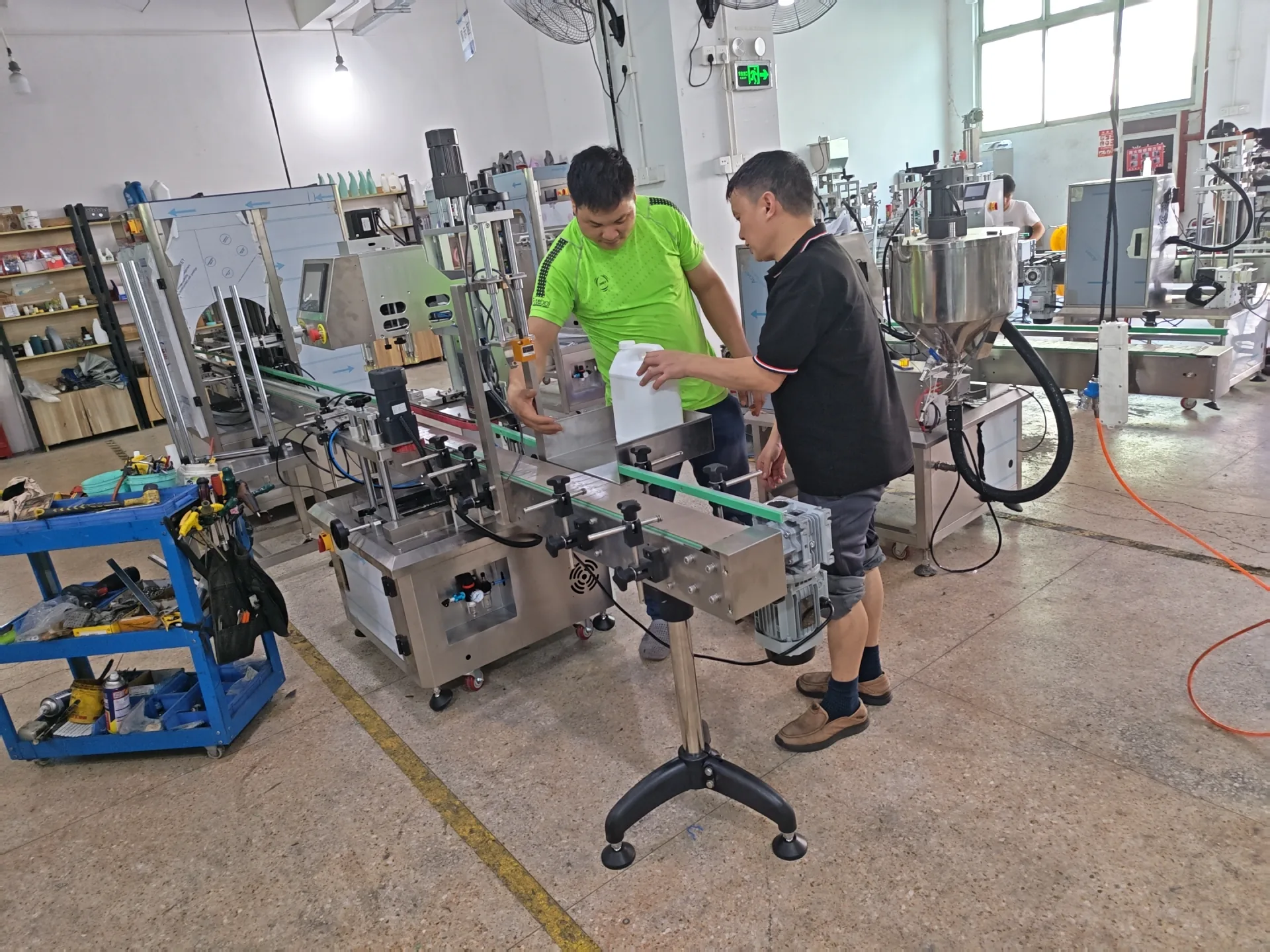 Technicians checking a bottle sample on packaging line equipment