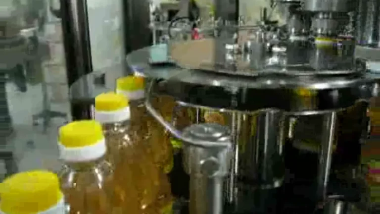 Yellow screw caps secured on edible oil bottles in the rotary capping section