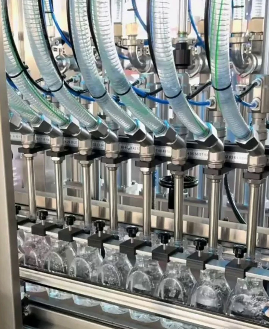Still frame of filling nozzles and clear bottles from the lubricant oil line video